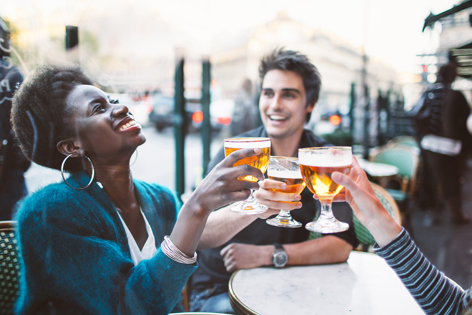 three people drinking beer outside smiling